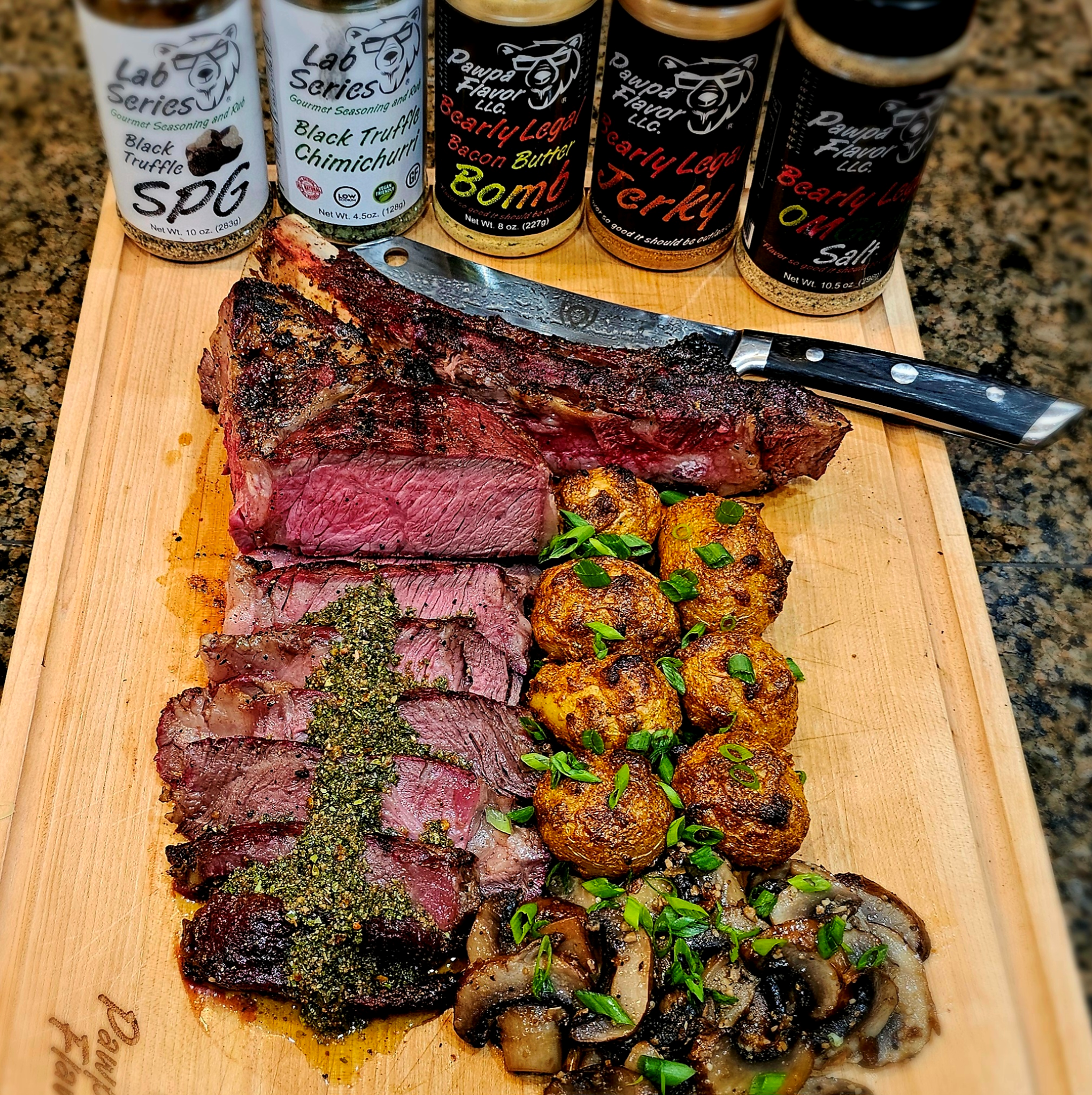 Reverse seared tomahawk ribeye steak sliced on a cutting board with crispy crust, topped with chimichurri, served with roasted potatoes and sautéed mushrooms, seasoned with Pawpa Flavor Black Truffle SPG, Bacon Butter Bomb, and Jerky rub
